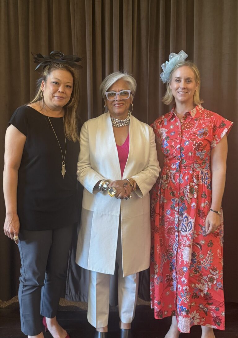 3 women standing in front of a brown curtain